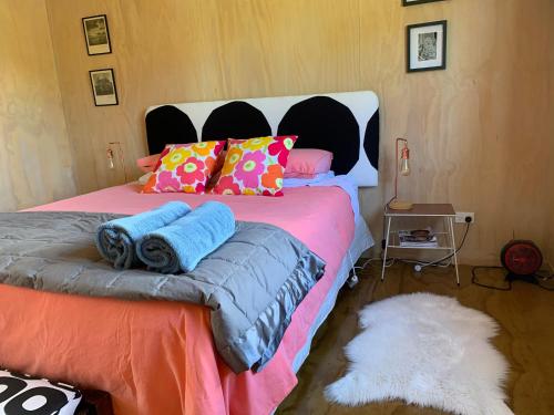 a bedroom with a large bed with colorful pillows at Fallow Hut in Masterton