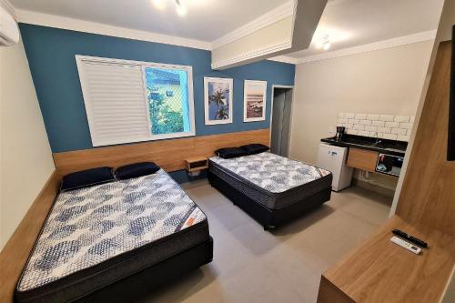 a room with two beds and a sink in it at Marmeu Enseada in Guarujá