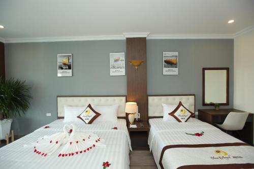 a hotel room with two beds and a mirror at Sea Angel Hotel Halong in Ha Long