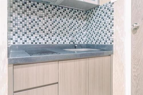 a bathroom with a sink and a tiled wall at Classic Studio Room Apartment at Taman Melati Surabaya By Travelio in Surabaya