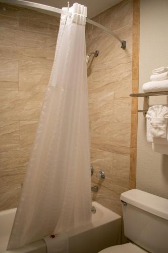 a bathroom with a shower with a white shower curtain at Days Inn by Wyndham Hillsboro TX in Hillsboro
