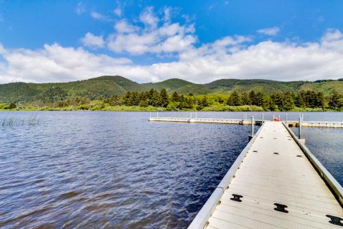 a dock on a lake with mountains in the background at Breakers Cottage in Rockaway Beach