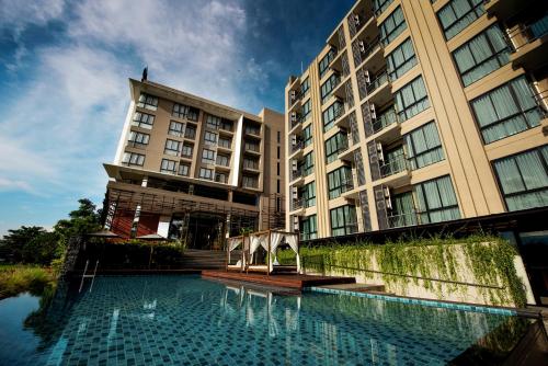 a hotel with a swimming pool in front of a building at Brique Hotel Chiangmai in Chiang Mai