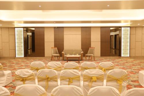 a room with white chairs and a table and a room with chairs at Sarovar Portico Rivera Ahmedabad in Ahmedabad