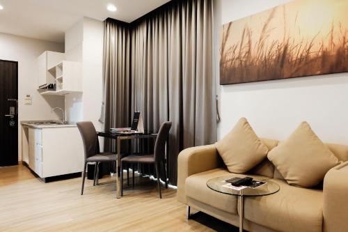 a living room with a couch and a table with a laptop at Brique Hotel Chiangmai in Chiang Mai