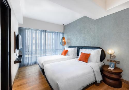 two beds in a hotel room with orange pillows at MAMAKA by Ovolo in Kuta
