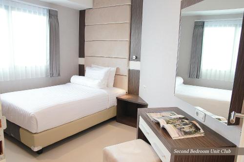 a hotel room with two beds and a mirror at Apartemen Puncak Marina in Surabaya