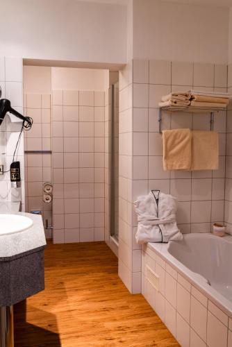 a white bathroom with a tub and a sink at Hotel Blauer Engel in Aue