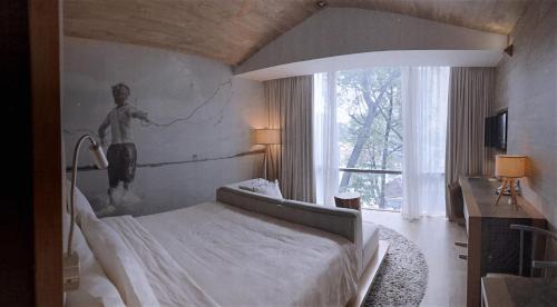 a bedroom with a bed with a painting on the wall at Fusion Suites Saigon in Ho Chi Minh City