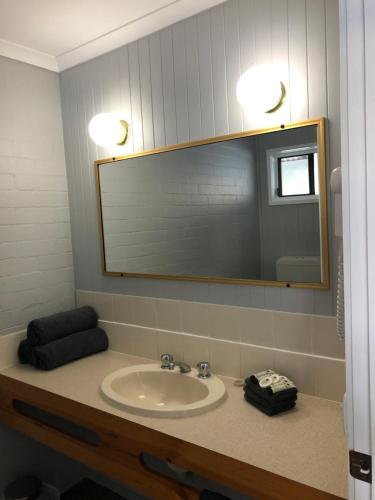 a bathroom with a sink and a mirror at Country Roads Motor Inn in West Wyalong