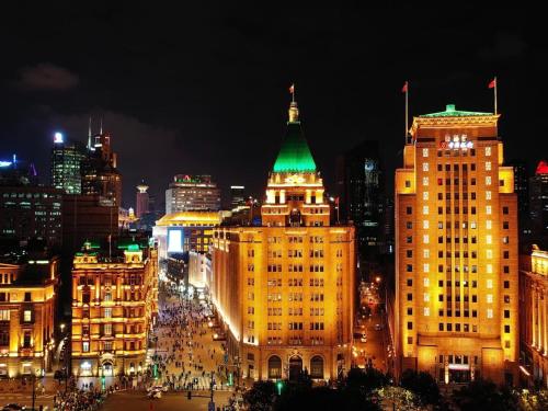a city lit up at night with a green roof at Fairmont Peace Hotel On the Bund (Start your own story with the BUND) in Shanghai