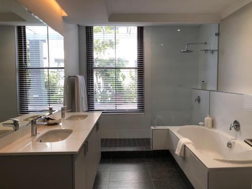 a bathroom with two sinks and a tub and a large mirror at Romney Park Luxury Apartments by The Stay Collection in Cape Town