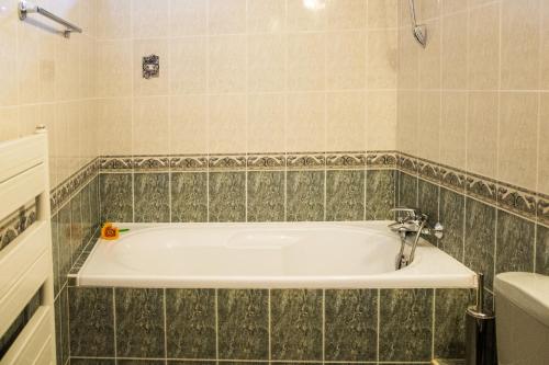 a white bath tub sitting next to a white sink at Family Hotel Elegance in Arbanasi