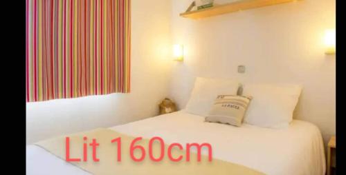 une petite chambre avec un lit avec des draps blancs et des oreillers dans l'établissement Mobil-home du Lac Mimizan, à Aureilhan