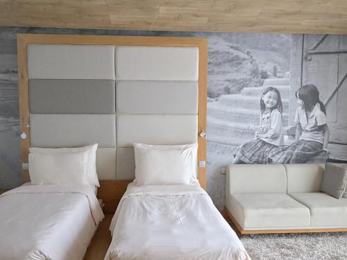 a room with two beds and a couch and a painting at Fusion Suites Saigon in Ho Chi Minh City