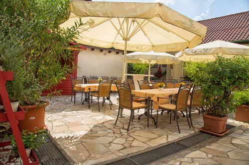 eine Terrasse mit Tischen, Stühlen und einem Sonnenschirm in der Unterkunft Hotel Krone in Hirschberg an der Bergstraße