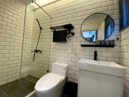 bagno bianco con servizi igienici e specchio di Kimen Yuyu B&B a Jinning
