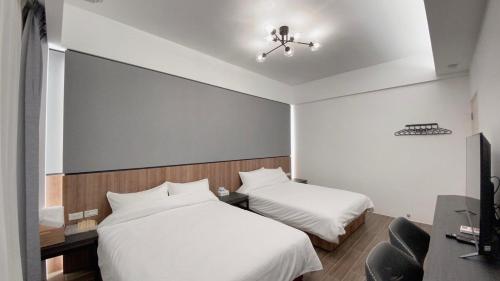 Una habitación de hotel con dos camas y un televisor. en Kimen Yuyu B&B, en Jinning