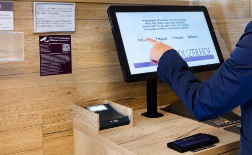 a person pointing at a computer screen with their index finger at Hotel Vaduzerhof by b-smart in Vaduz