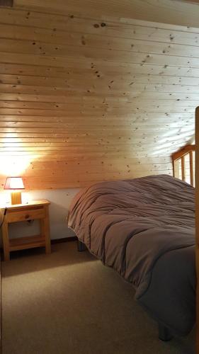 une chambre avec un lit et un mur en bois dans l'établissement RED APPLE CARROZ Duplex de charme WIFI Parking Balcon TV Ski-Bus, aux Carroz d'Arâches