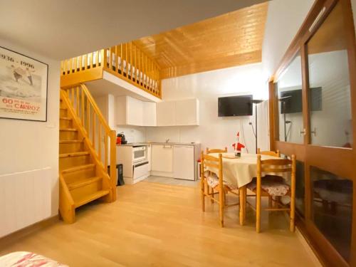 a kitchen and dining room with a table and a staircase at RED APPLE CARROZ Duplex de charme WIFI Parking Balcon TV Ski-Bus in Les Carroz d'Araches