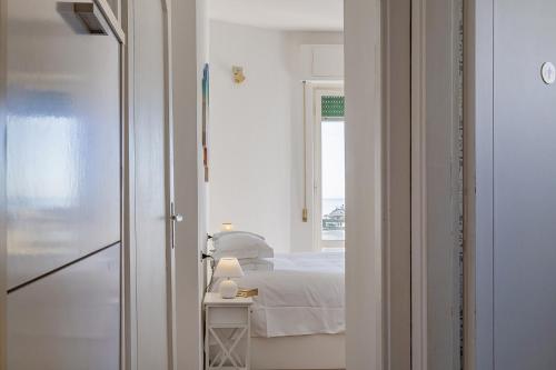 Cette chambre blanche dispose d'un lit et d'une fenêtre. dans l'établissement Homey Seaview Apartment by Wonderful Italy, à Gênes