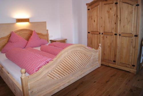 a bedroom with a wooden bed with red pillows at Bichlhof in Niederthai