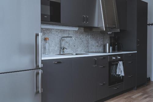 a kitchen with black cabinets and stainless steel appliances at Magnolia House Norrviken in Sollentuna