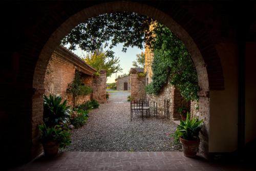 an archway leading into a courtyard with plants at Castello di Bossi in Castelnuovo Berardenga