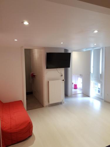 a living room with a red couch and a flat screen tv at Chambres d'hôtes les 2G in Boësse