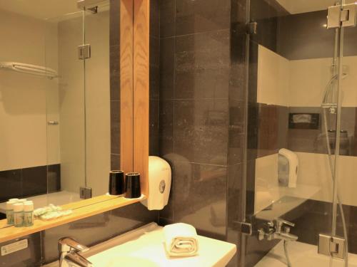 a bathroom with a shower with a sink and a mirror at Le Pietri Urban Hotel in Rabat
