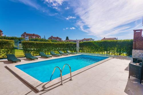 a swimming pool with lounge chairs next to a hedge at Villa Berenice in Butkovići