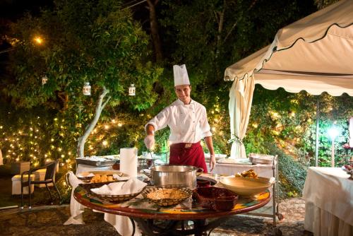 a chef standing in front of a table with food at Hotel Sierra Silvana in Selva di Fasano