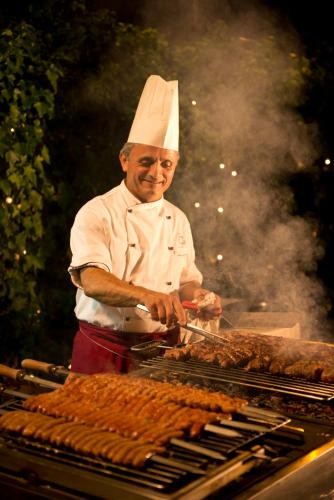 a man in a chefs hat cooking food on a grill at Hotel Sierra Silvana in Selva di Fasano