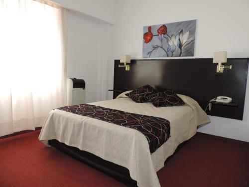 ein Schlafzimmer mit einem großen Bett und einem Telefon in der Unterkunft KRAKUS in San Bernardo