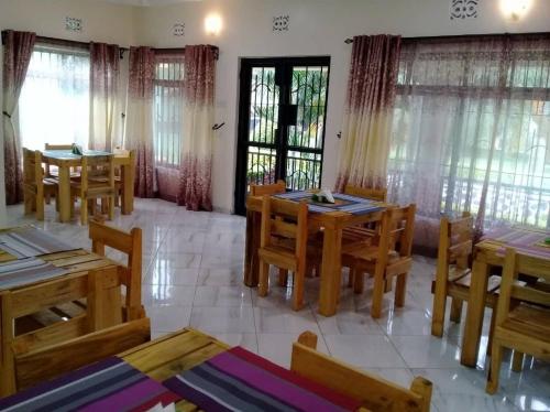 uma sala de jantar com mesas e cadeiras de madeira e janelas em Africa Lodge Arusha em Nkoaranga