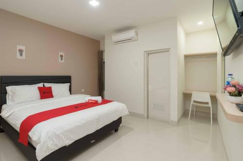 a bedroom with a bed with a red cross on it at RedDoorz Plus near Eka Hospital BSD 5 in Tangerang
