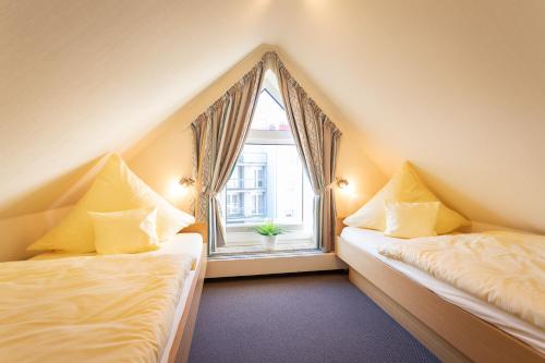 2 Betten in einem Zimmer mit Fenster in der Unterkunft Sanddornhaus in Norderney