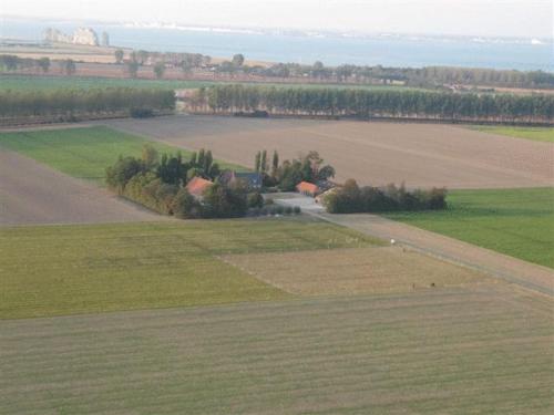 an aerial view of a large field with a farm at Bed & Breakfast de Kienstee in Schoondijke