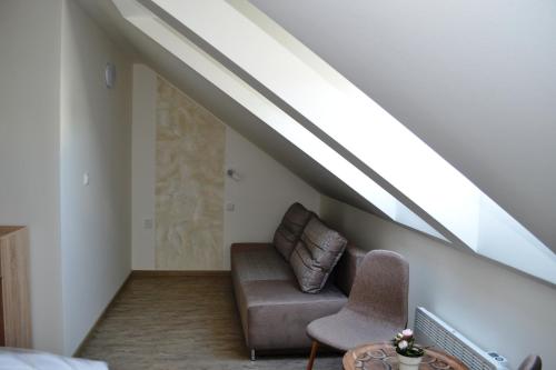 a living room with a couch under the stairs at Penzion Sedlecká vína in Sedlec