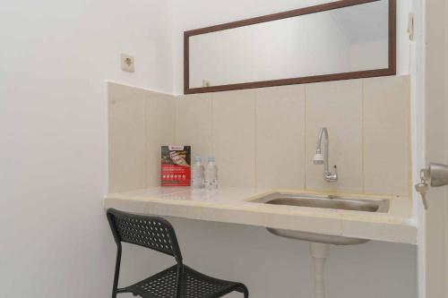 a bathroom with a sink and a chair and a mirror at RedDoorz Syariah near Exit Toll Jatiwarna 2 in Pondokmelati