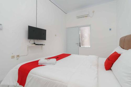 a white bedroom with a bed with a tv on the wall at RedDoorz Syariah near Exit Toll Jatiwarna 2 in Pondokmelati