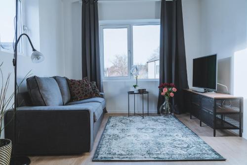 a living room with a couch and a television at Magnolia House Norrviken in Sollentuna