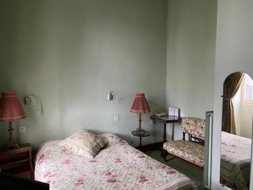 a bedroom with two beds and a table with a lamp at Cit'Hotel Marie Stuart in La Roche-sur-Yon