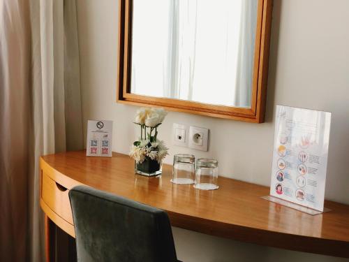 a desk with a vase of flowers and glasses on it at Le Pietri Urban Hotel in Rabat