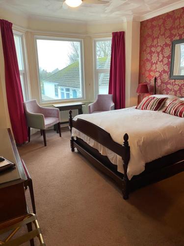 a bedroom with a bed and a desk and windows at The Kingswood Guest House - Adult Only in Weymouth