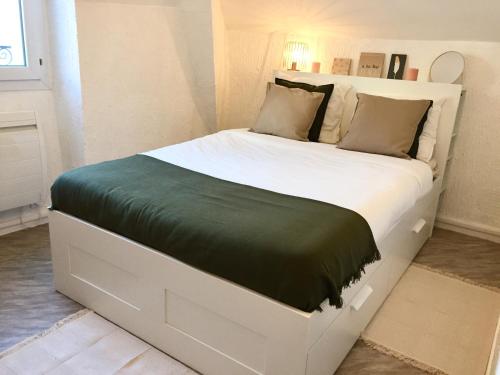 ein großes weißes Bett mit einer grünen Decke darauf in der Unterkunft Appartement bord de mer centre-ville, proche gare in Le Pouliguen