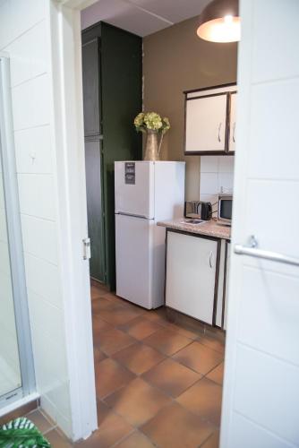 a kitchen with white appliances and a tile floor at Melrose Place Guestrooms in Potchefstroom