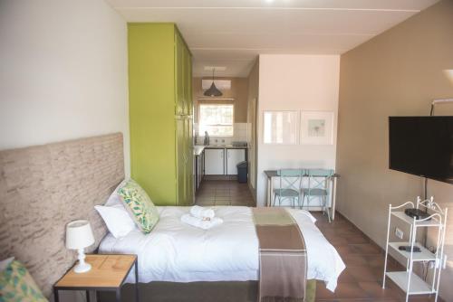 a bedroom with a white bed and a television at Melrose Place Guestrooms in Potchefstroom