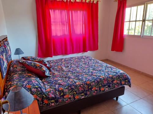 1 cama en un dormitorio con cortinas rojas en Terra Vista en Huerta Grande